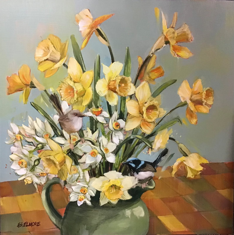 2 small fairy wrens perch amongst golden daffodils and jonquils in a green jug set on a checked tablecloth of oranges & yellows against a soft grey background
