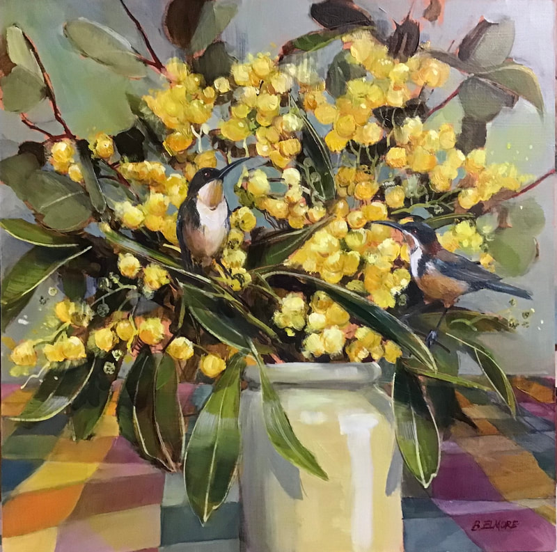 2 spinebill birds perch in an arrangement of wattle leaves and golden wattle flowers in stone vase set on a colourful check tablecloth in orange and pink tones
